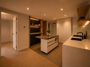 Une cuisine moderne dotée d’un îlot central, d’appareils électroménagers intégrés et d’un design minimaliste.