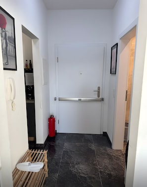 A hallway with a white door, a fire extinguisher, a telephone, and a shoe rack. - Holiday Home 'Saarpanorama Apartment' with Balcony, Wi-Fi and Air Conditioning (Saarbrücken)