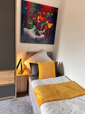 Une chambre à coucher moderne avec un lit, des oreillers, une table de chevet et un tableau accroché au mur.