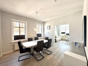 Ein moderner Wohnbereich mit Essplatz, einer Couch und einem Fernseher.