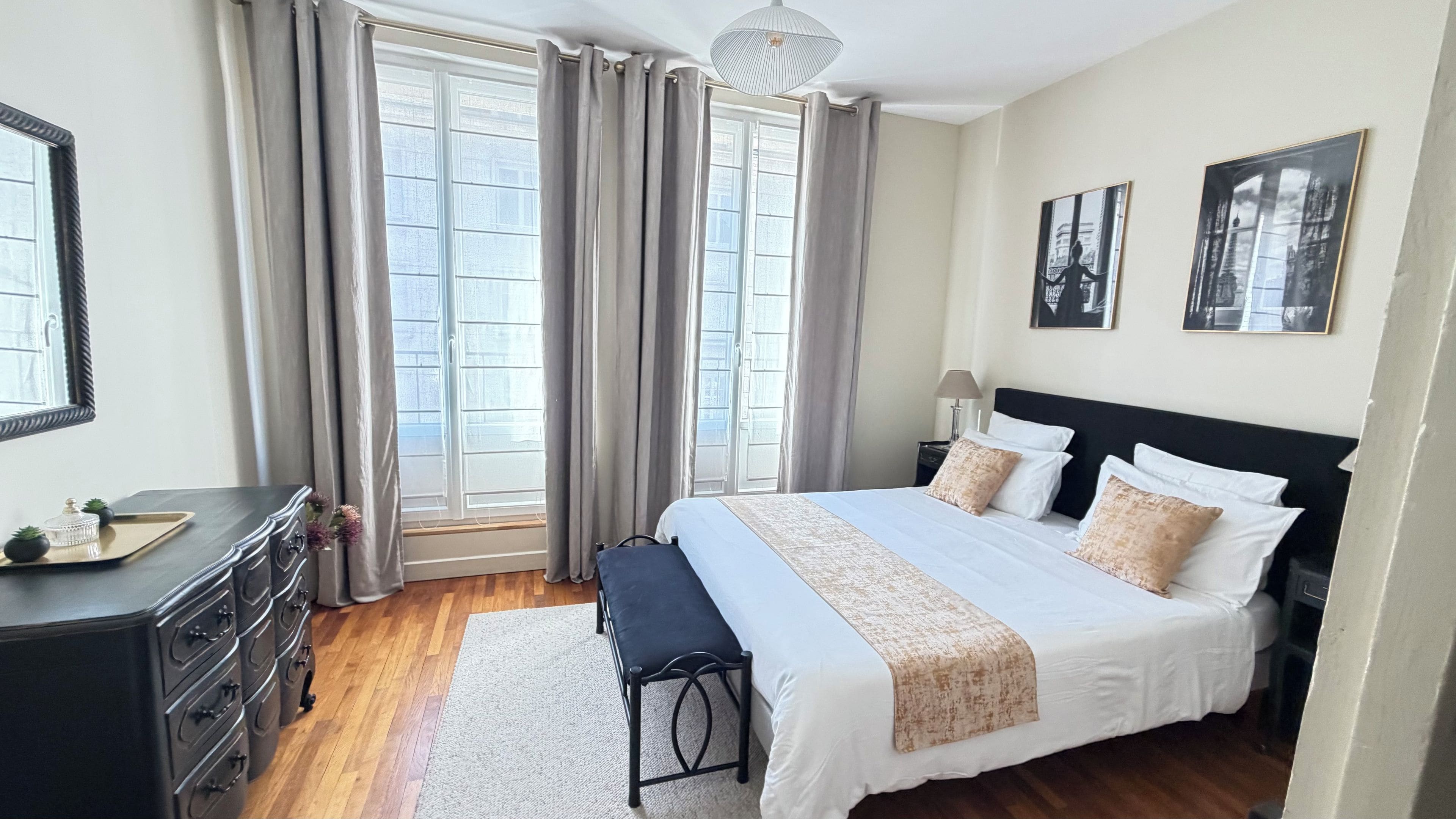 Une chambre d’hôtel avec un grand lit, des tables de chevet, un bureau et une fenêtre avec des rideaux.