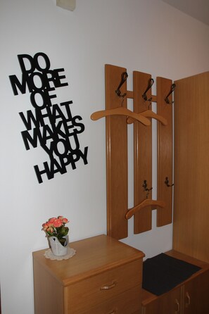 A room with a wooden wardrobe, a wall-mounted coat rack, a small wooden dresser with drawers, and a vase with flowers on top. - Vacation Rental on the Ilsenbach, 105 m², Right in the Heart of the Village (Lügde)