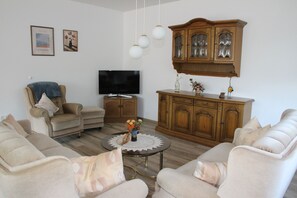 A living room with a sofa set, a television, a cabinet, and a coffee table. - Vacation Rental on the Ilsenbach, 105 m², Right in the Heart of the Village (Lügde)