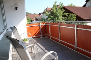 A balcony with a metal railing, a small table with a potted plant, and two chairs. - Vacation Rental on the Ilsenbach, 105 m², Right in the Heart of the Village (Lügde)