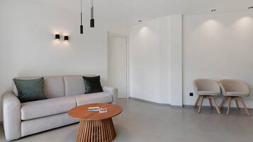 A modern living room with a sofa, two chairs, a coffee table, and pendant lighting.