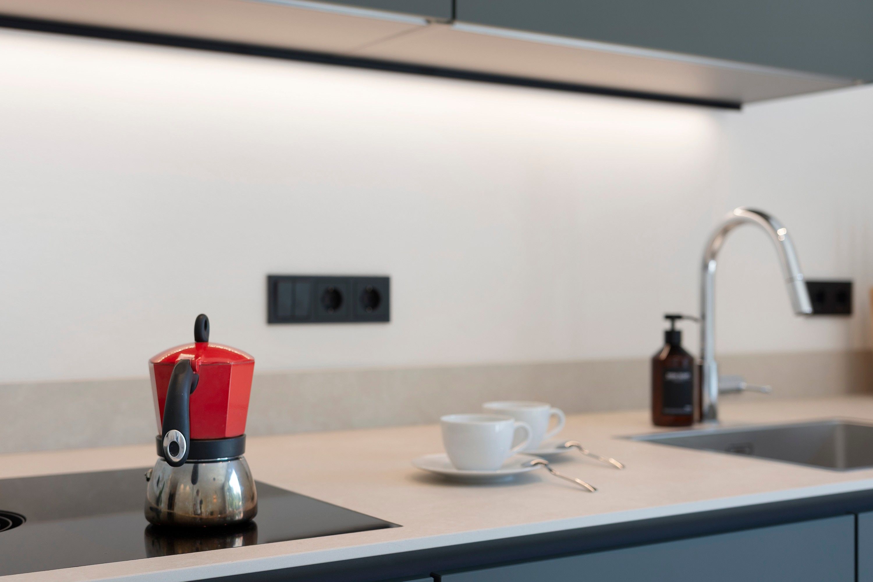 Eine moderne Küche mit Wasserkocher, Kaffeetasse und Seifenspender.
