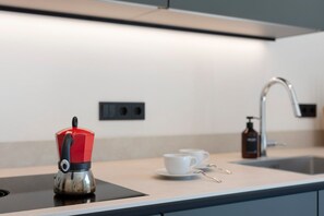 Et moderne køkken med elkedel, kaffekop og sæbedispenser.