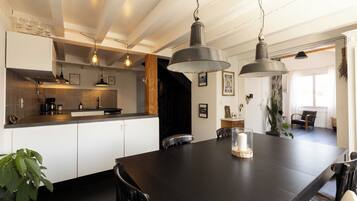 A modern kitchen with white cabinets, a dark wooden dining table, and pendant lighting.