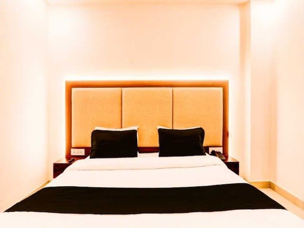 Ein Hotelzimmer mit einem großen Bett, einem Kopfteil mit hellem Panel und zwei Nachttischen mit Lampen.