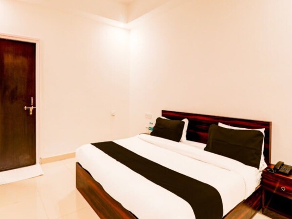 Una habitación de hotel con una cama, una mesita de noche y una puerta.