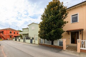Une rue résidentielle bordée de maisons, avec un arbre et un ciel dégagé.