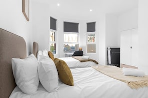 Une chambre d’hôtel moderne avec deux lits, un bureau et vue sur la rue.