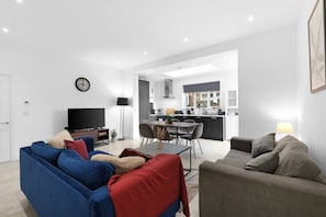 Un salon moderne avec un canapé bleu, un canapé gris et un coin repas comprenant une table et des chaises.