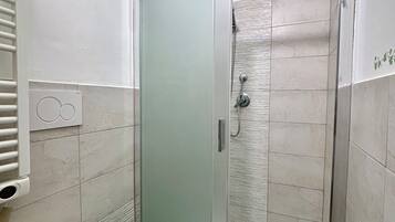 Un bagno con doccia in vetro, un water e un appendi asciugamani.