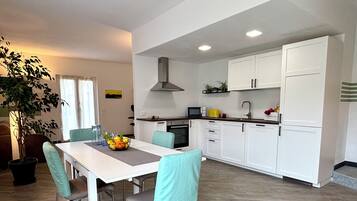 Une cuisine moderne avec des meubles blancs, une table à manger avec des chaises et une plante en pot.