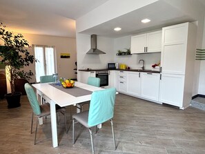 Una cocina moderna con armarios blancos, una mesa de comedor con sillas y una planta en maceta.