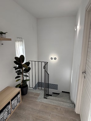 A staircase with a metal railing, a potted plant, and a wooden bench.