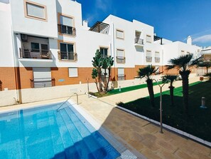 A modern building with a swimming pool, balconies, and a well-maintained lawn. - Apartment 'Quinta Da Gomeira 68' with shared pool, Wi-Fi and air conditioning (Tavira)