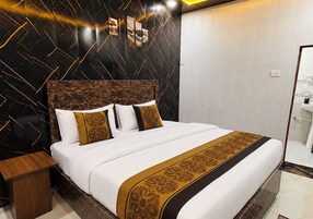 Habitación de hotel con una cama grande, una mesita de noche de madera y un baño visible a través de una puerta abierta.