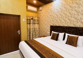 Una habitación de hotel con una cama grande, cabecera de madera y pared con estampado.