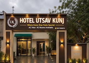 La entrada al Hotel Utsav Kunj con un letrero que indica habitaciones con aire acondicionado y sin aire acondicionado disponibles.