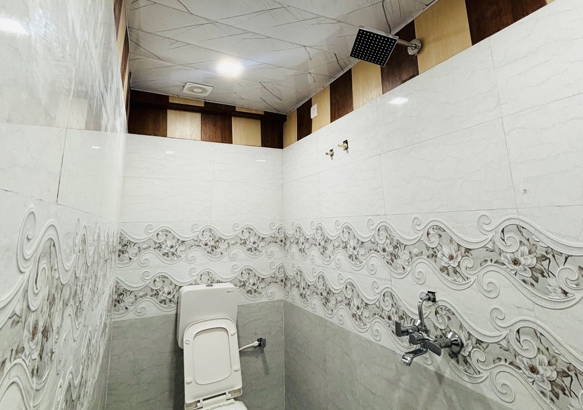 A restroom with a toilet, a hand dryer, and a wall-mounted faucet.