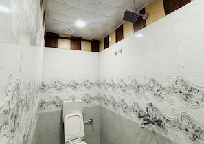 A restroom with a toilet, a hand dryer, and a wall-mounted faucet. - Hotel Utsav Kunj (Sitapur)