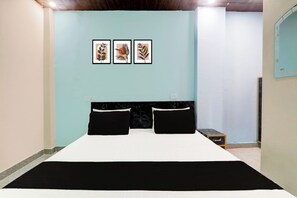 Un dormitorio con cama, dos almohadas negras, un cabecero de mármol y tres cuadros enmarcados en la pared.