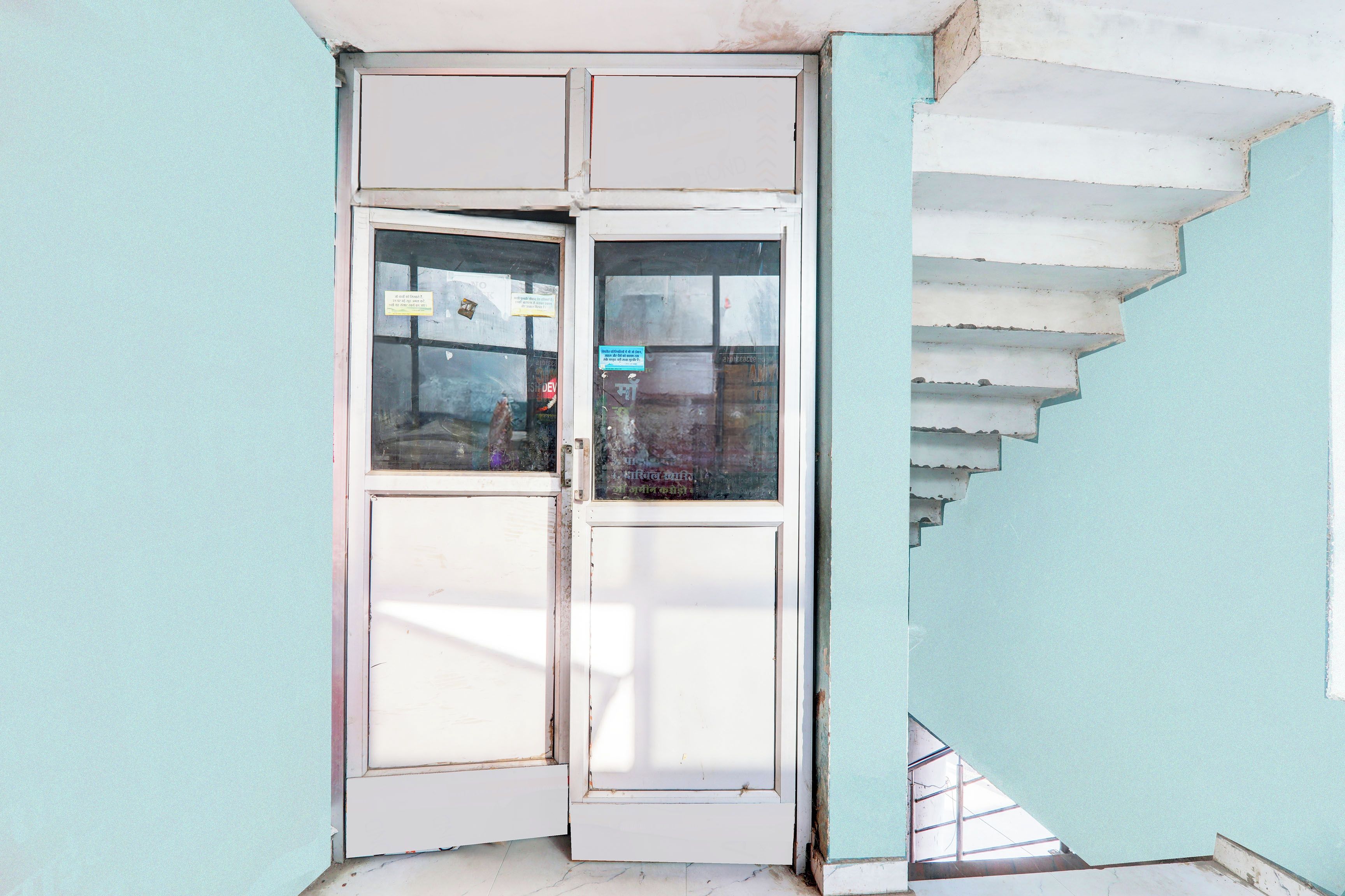 Una esquina de un edificio con una puerta blanca y una escalera.