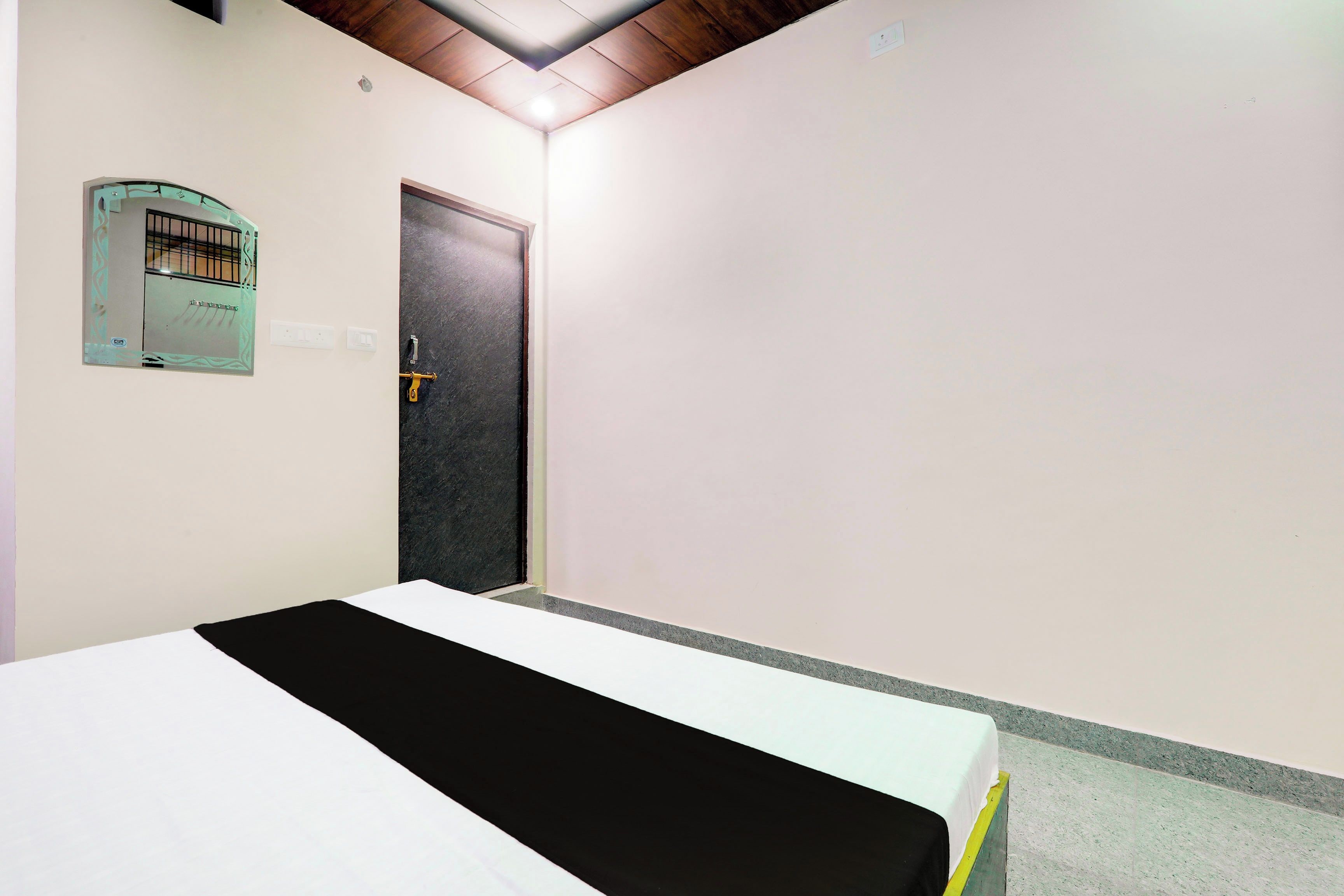 Quarto com cama, porta e luminária fixada na parede.