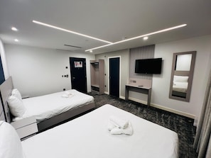 Une chambre d’hôtel avec deux lits, une télévision, un miroir et une armoire.