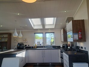 A modern kitchen with skylights, a central island, and a view of the outdoors. - Chapel Farm The Lucky Lodge No 7 (Appleby-in-Westmorland)