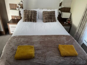 A neatly made bed with two pillows and two towels. - Chapel Farm The Lucky Lodge No 7 (Appleby-in-Westmorland)