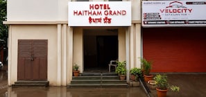 Una entrada de hotel con un letrero que dice 'HOTEL HAITHAM GRAND' y un centro de servicios cercano llamado 'VELOCITY'.