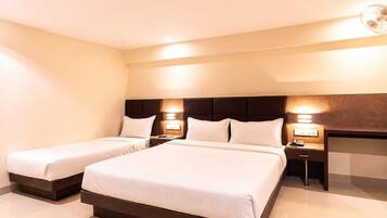 A hotel room with two beds, a dark headboard, bedside lamps, and a flat-screen TV.