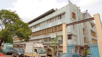 A multi-story building with a flat facade, parked vehicles, and a gated entrance.