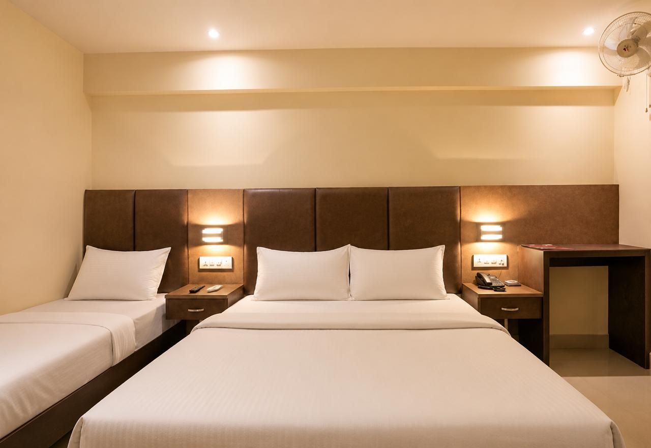 A hotel room with two single beds, a desk, and a chair.