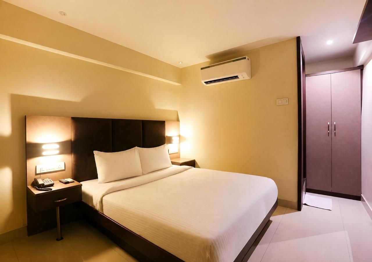 A hotel room with a bed, bedside table, lamp, and wardrobe.