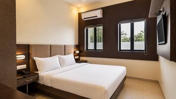 A modern hotel room with a large bed, bedside tables, an air conditioning unit, and a TV mounted on the wall.