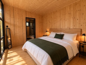 A wooden-paneled bedroom with a bed, bedside lamps, and a large mirror. - River and Ridge (Tierpoort)
