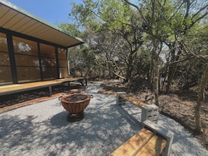 A wooden bench, a stone table, and a building with large windows. - River and Ridge (Tierpoort)