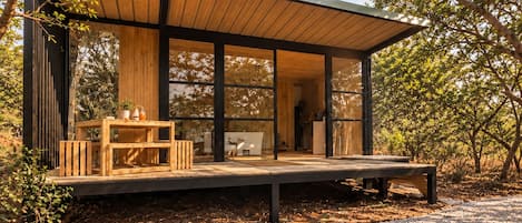 Ein modernes Holzgebäude mit großen Glasfenstern, einer Holzterrasse und einem Kiesweg.