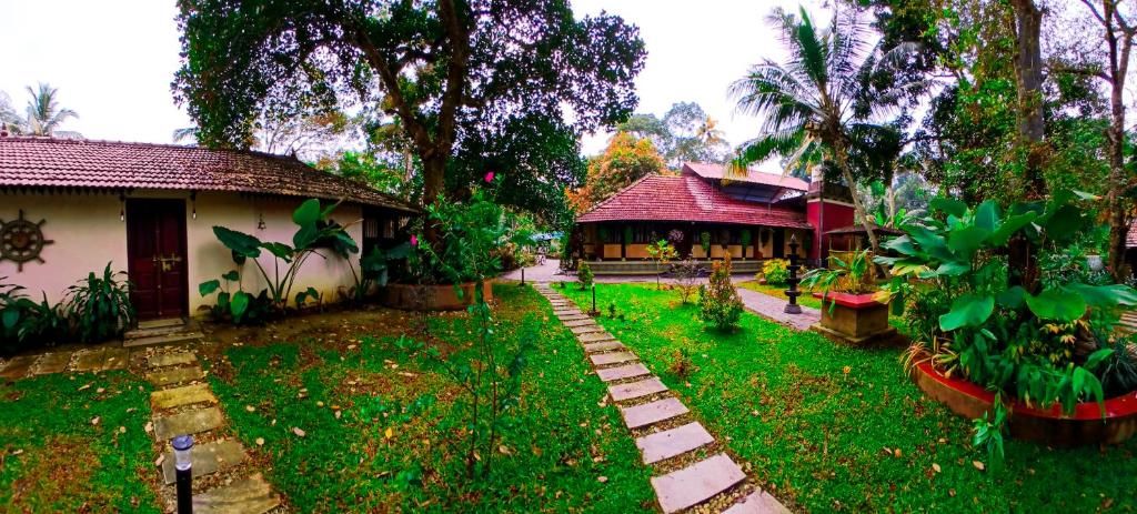 Un sendero de jardín que conduce a un edificio con techo rojo, rodeado de abundante vegetación y palmeras.