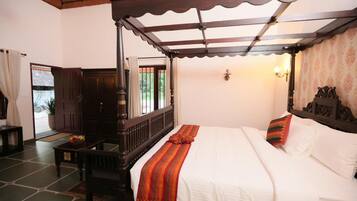 A traditional room with a four-poster bed, a wooden desk, and a view of the outdoors through a window.