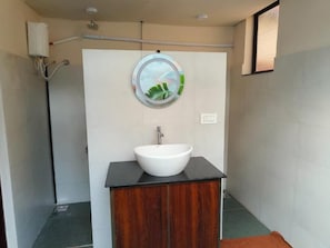 Une salle de bain avec un lavabo blanc, un meuble en bois et un miroir rond offrant une vue sur un paysage.