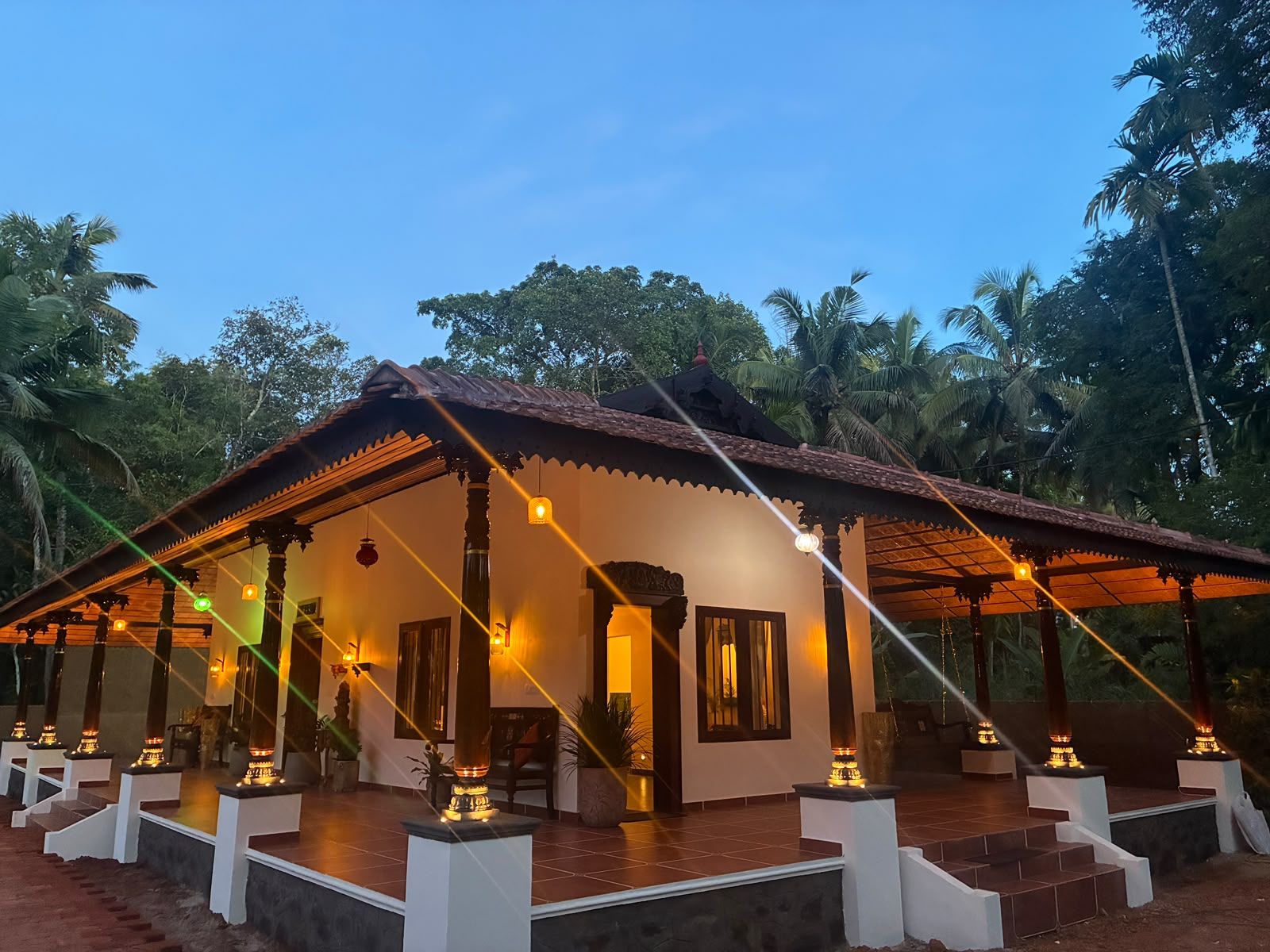 A traditional house with a tiled roof, multiple windows, and a porch area with steps leading to the entrance.