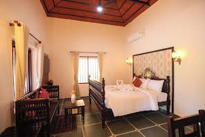 Une chambre d’hôtel équipée d’un lit, d’un bureau, d’une chaise, d’une fenêtre avec des rideaux et d’un ventilateur de plafond.