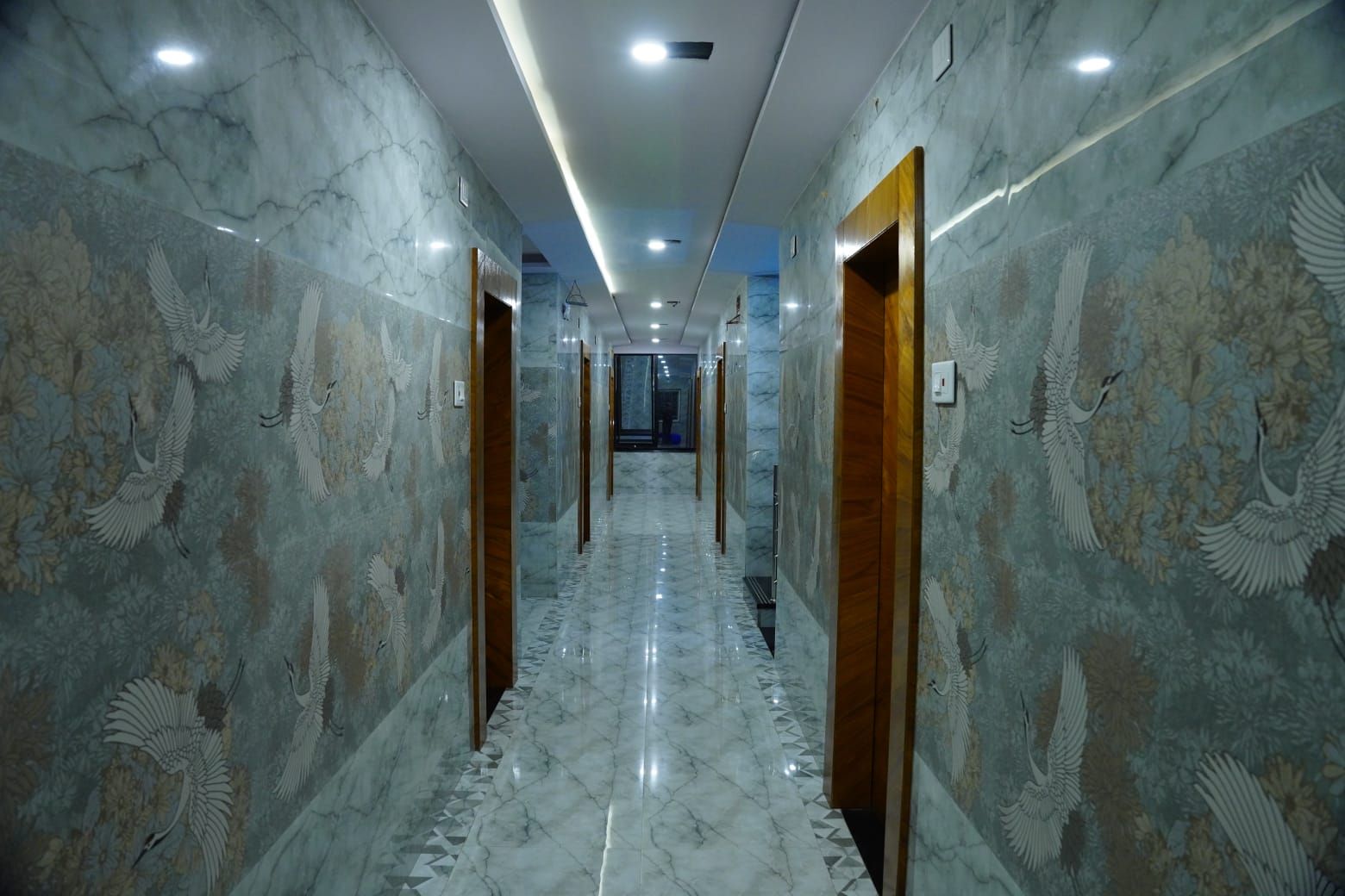 A hallway with marble walls and floors, featuring wall art of birds.