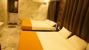 Habitación de hotel con dos camas, baño y zona de ducha.