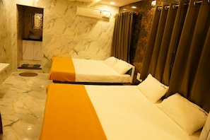 Habitación de hotel con dos camas, baño y zona de ducha.
